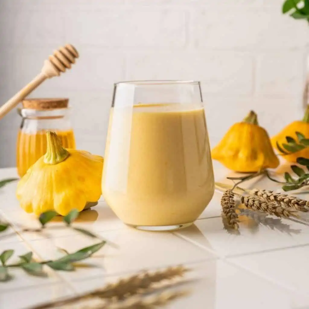 Adrenal support cocktail drink recipe in a clear glass on table with fresh honey and flowers for a healthy gut.