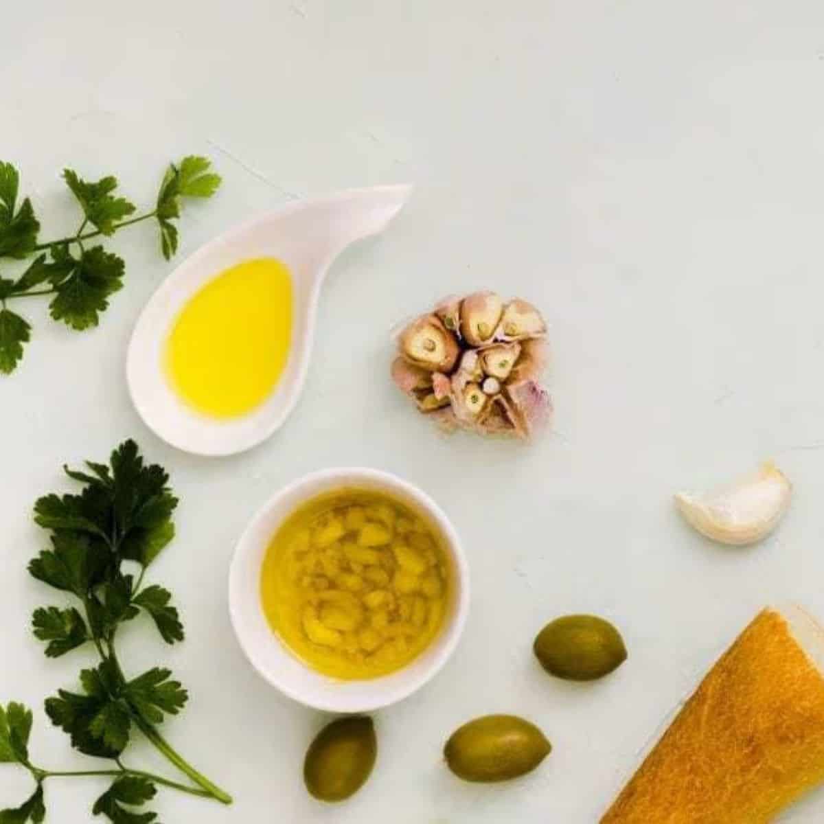 Apple cider vinegar on a white table with herbs and garlic.