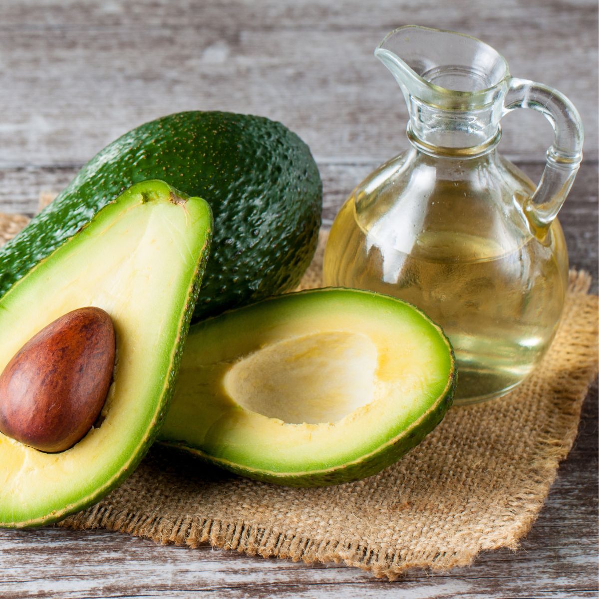 Avocado oil on a brown tablecloth with fresh avocado, make tamari ginger marinade, homemade mayonnaise, and creamy lemon basil dressing,
