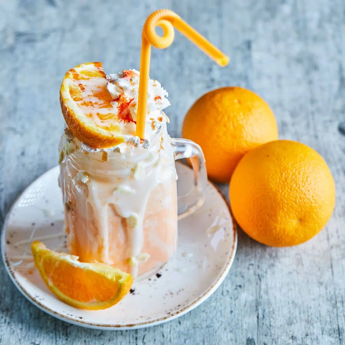 Healthy orange creamsicle smoothie in a mason jar topped with whipped cream and oranges.