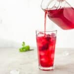 Iced Red raspberry rooibos healthy tea recipe being poured into a glass.
