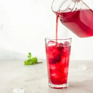 Iced Red raspberry rooibos healthy tea recipe being poured into a glass.