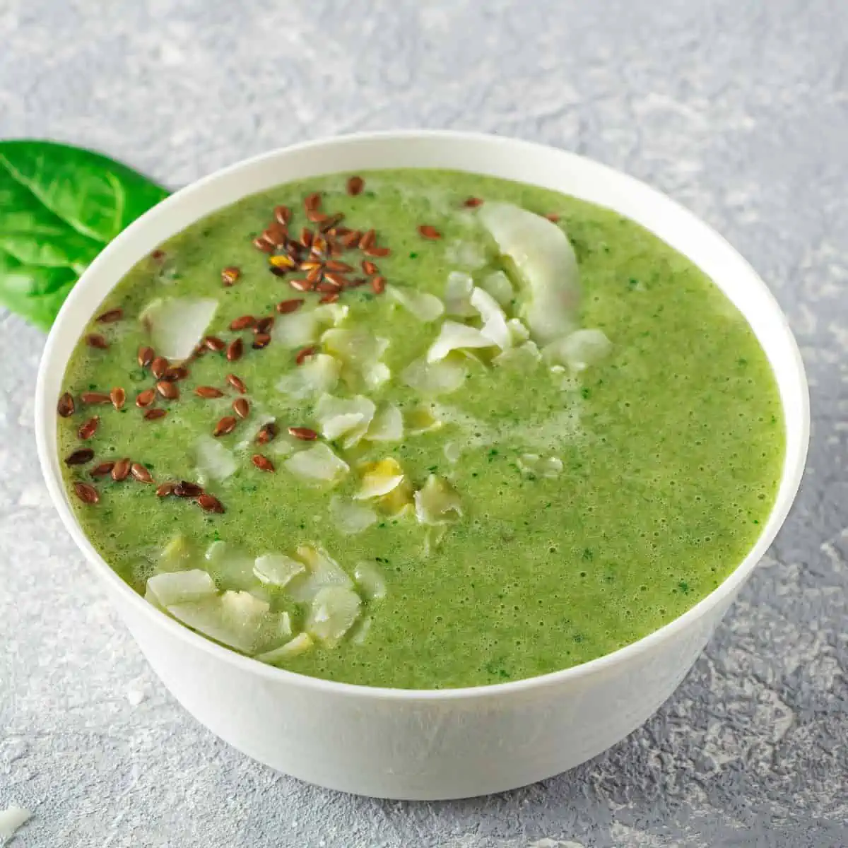 avocado smoothie bowl topped with flax seeds in a white bowl.