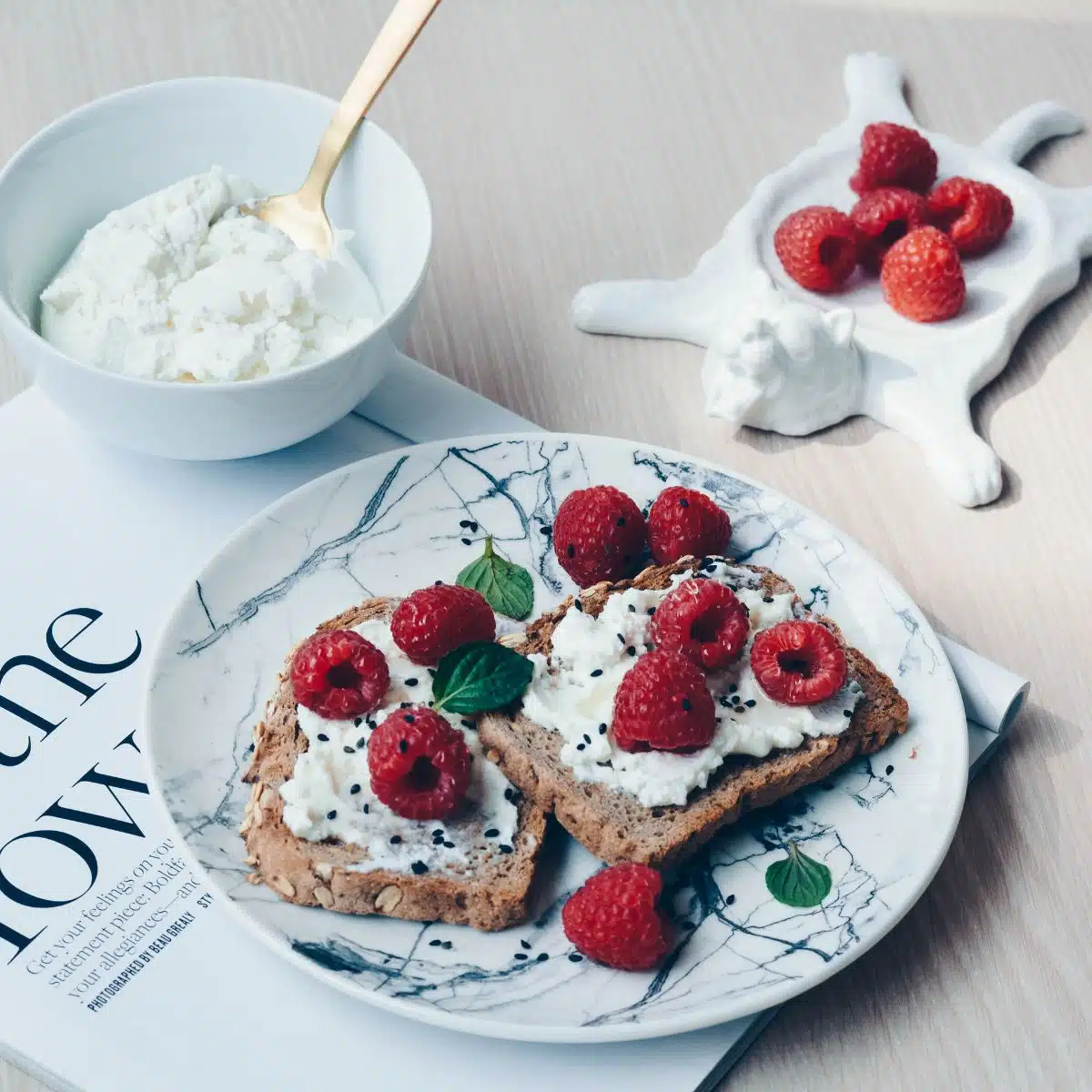 Healthy raspberry yogurt topped toast on a plate with fresh raspberries.
