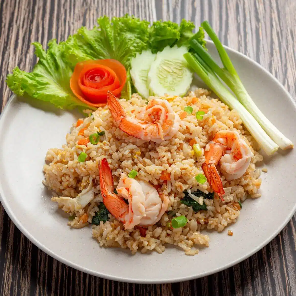 shrimp fried rice on a white plate with vegetables